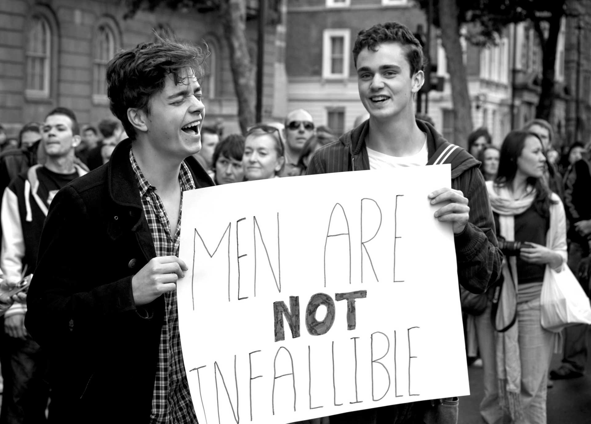 To menn holder et skilt der det står ‘Men are not infallible’.